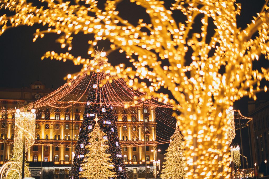 Photo from an outdoor christmas holiday light display showing christmas lights decorating a house and it's surrounding trees.